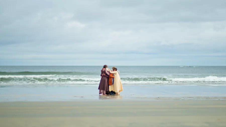 members of artist collective on beach, embracing 