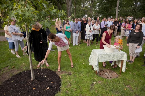 Pouring water on a tree planted in memory of faculty and staff who died in the previous year.