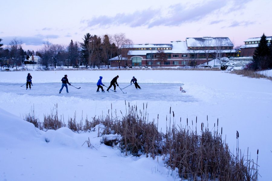 A group of Lewiston High School alumni home from college play afternoon pickup hockey game on the Puddle. (Phyllis Graber Jensen/Bates College)