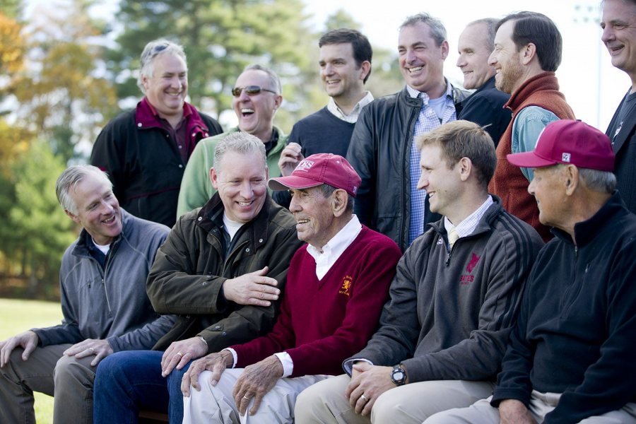 Chick Leahey '52 is surrounded by his former players, along with head coach Mike Leonard (second from right) and longtime assistant Bob Flynn (right) during a ceremony to retire Leahey's number 11 and dedicate a new hitting facility at Leahey Field. (Phyllis Graber Jensen/Bates College)