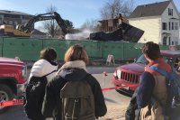 Students pause on their way to class to watch the demolition of 145 Nichols St. on March 28. (H. Jay Burns/Bates College)