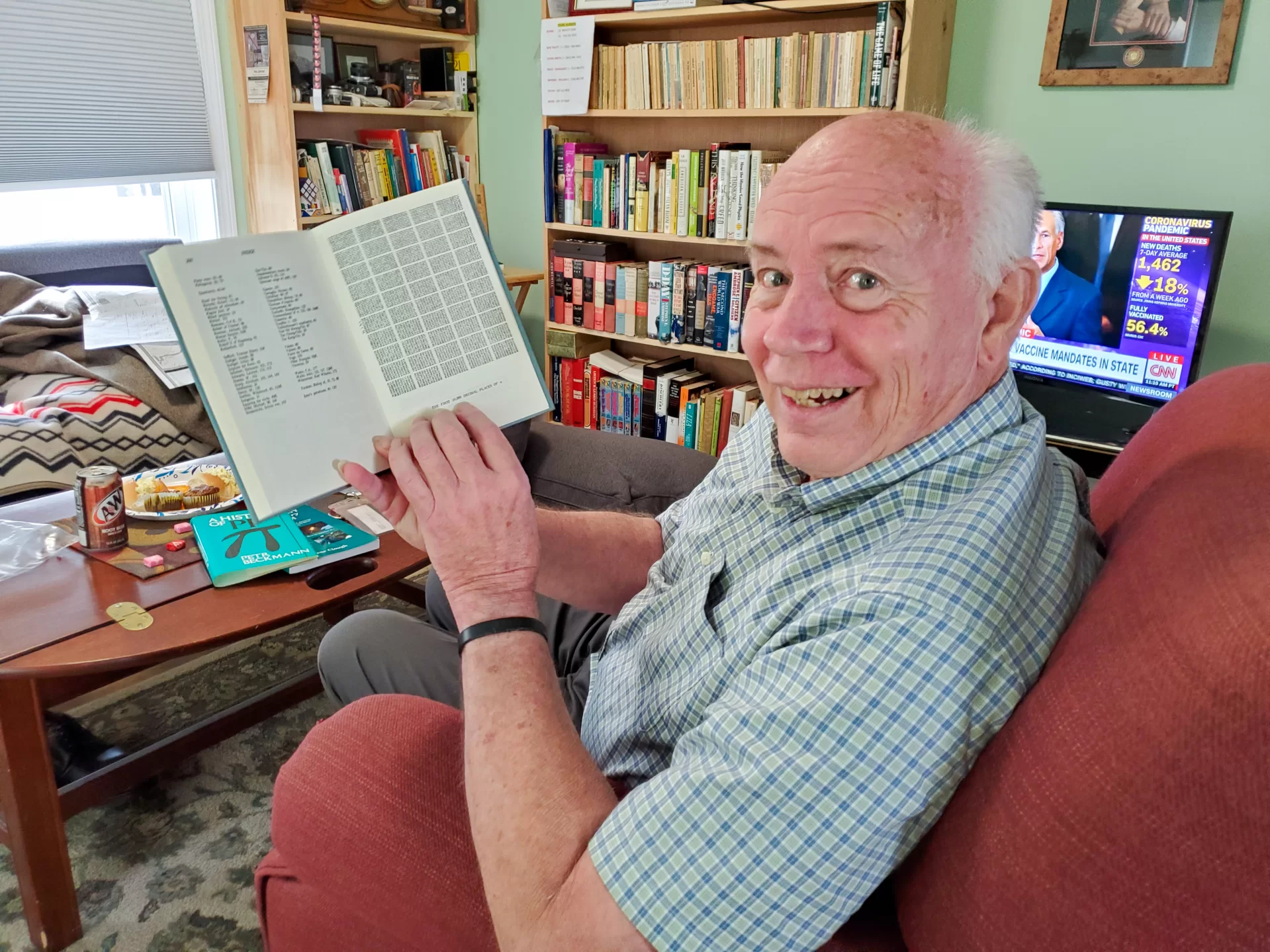 Gene Clough holds <em> A History of Pi</em> open to a page showing pi out to many decimal points. Clough, who has age-related demential, can still recite pi out to 50 places. (Freddie Wright/Bates College)