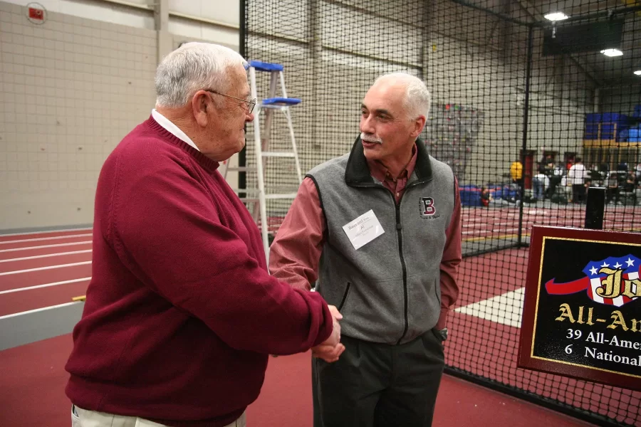 Feb. 7, 2009: Fereshetian congratulates throwing coach Joe Woodhead at the dedication of the throwing areas in Merrill Gym in honor of the longtime coach. (Louisa Demmitt ’09 for Bates College)