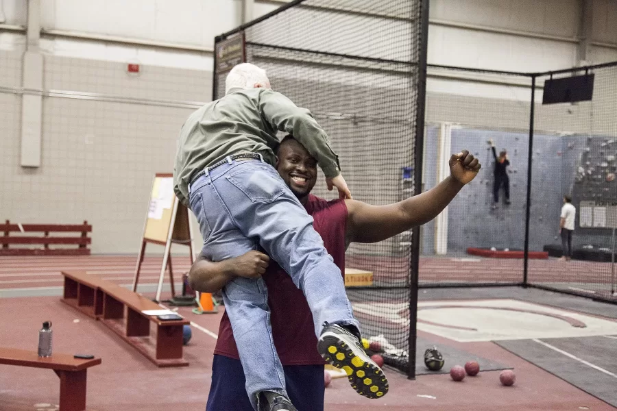 March 8, 2016: Fereshetian being picked up by thrower Adedire Fakorede ’18 during final preparations for that year's NCAA Division III Indoor Track and Field Championships. (Phyllis Graber Jensen/Bates College)