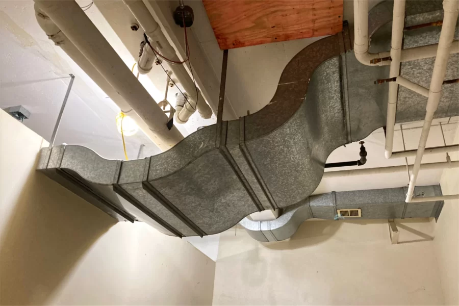 This old air duct in the basement of 96 Campus Avenue displays intriguing curves that originally made way for other ceiling pipes and conduits. Now disused, the duct and others like it will be removed. (Doug Hubley/Bates College)