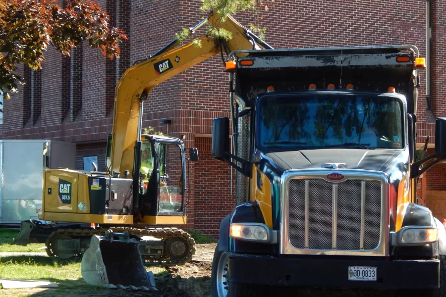 An excavator and dump truck are removing a driveway that’s no longer needed in front of 96 Campus Avenue. (Doug Hubley/Bates College)
