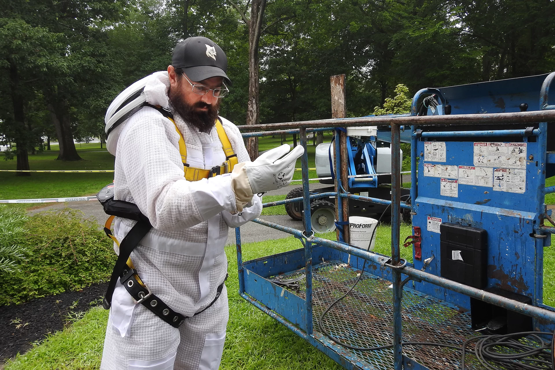 Brian Mason of Spicer Bees (purple shirt) removes a big honeybee hive from the college's oldest building, Hathorn Hall, on July 25, 2024.

Discovered by a work crew painting the Hathorn trim, the hive was in a section of the soffit of the Hathorn portico, where the roof joins the main part of the building. 

Lifted to the second-story location by a Genie boom lift, Mason and Bates carpenter Matt Capone, with beard, worked together, the latter using a multitool and pry tools to remove trim to get at the hive, and the former using a homemade vacuum and hive tools to remove the bees and comb, relocating as much of the hive as possible to his apiary in Whitefield. 

Mason, who estimated the hive at upwards of 50,000 bees, gives credit to Bates for calling in a beekeeper for the project. "100 percent credit," he says, noting that the Bates hive was not only healthy but had apparently survived for at least one winter, if not more. Most wild honeybee hives die each winter, and commercially maintained hives typically rely on treatments to control mites.

"Less human intervention is always valuable. The fact that this hive wintered without intervention means the bees might just have something going for them to survive. So now I can introduce the Bates bees into my apiary. That’s a win."