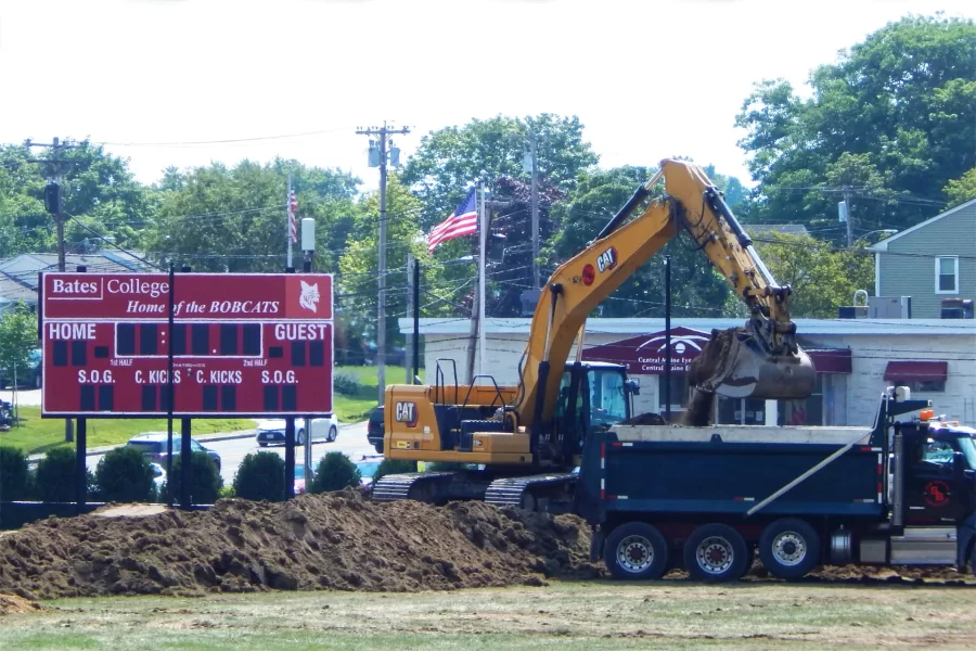 An excavator loads dirt and sod into a dump truck for disposal at Russell Street Field as the replacement of natural grass with artificial turf gets underway on July 15. Some of the dirst will be sifted and reused in landscaping elsewhere on the site. (Doug Hubley/Bates College)