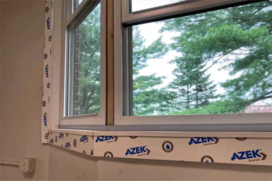 Used at 96 Campus Avenue as window trim and other purposes, Azek is a manufactured building material. The brand name is printed on a protective film that will be peeled off prior to painting. The trees are part of the view from the eastern side of the building. (Doug Hubley/Bates College)