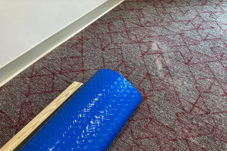 A splash of daylight on new carpeting in a second-floor seating area at 96 Campus Avenue. The blue material will be rolled out to protect the new carpet from incidental damage. (Doug Hubley/Bates College)