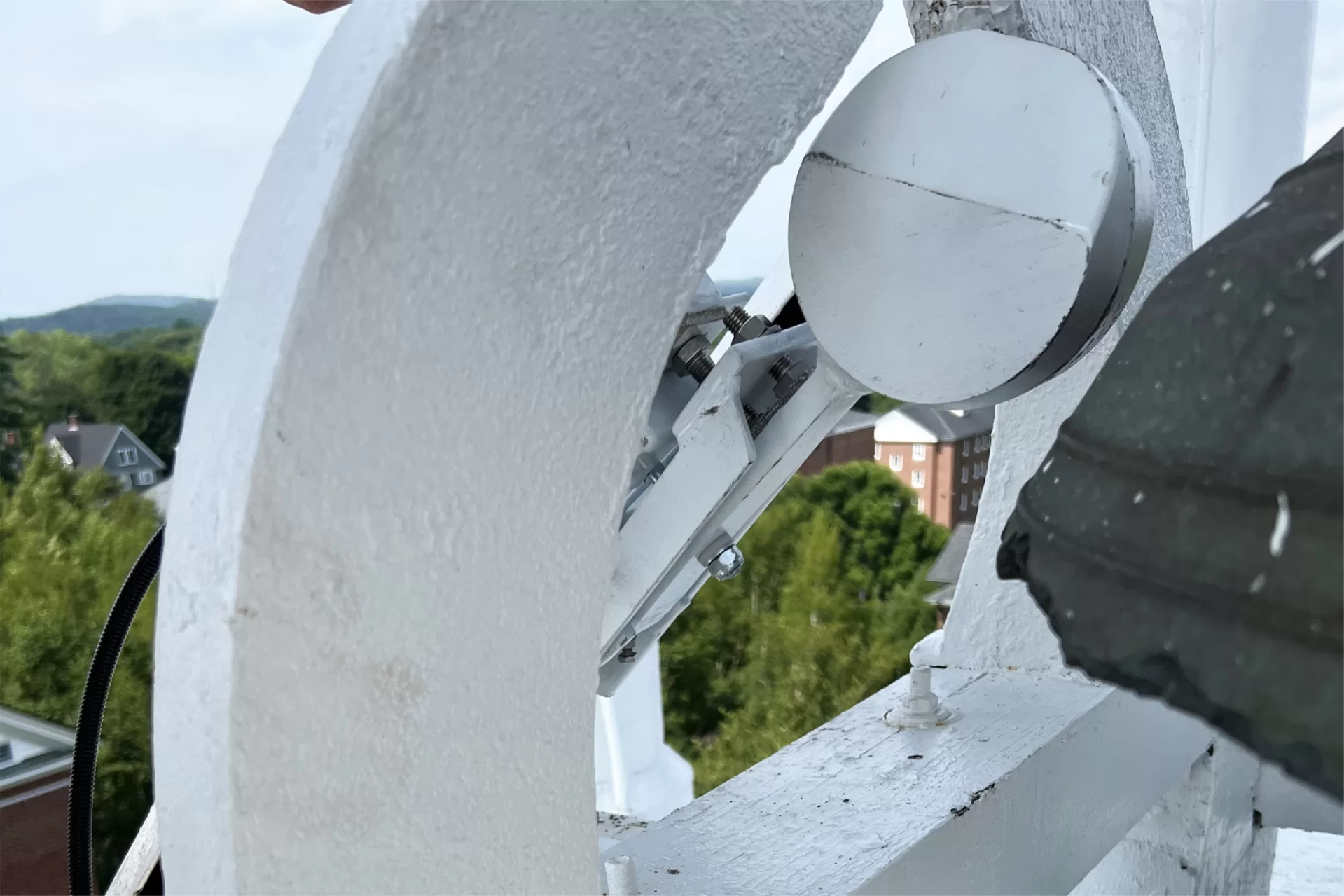 The new Hathorn Hall bell striker is the rounded white object at top right. The bell itself is the dark gray shape at right — notice the wear on the sound bow, around the bottom of the bell, from 167 years of use. (Yamil Peralta Burgos/Bates College)