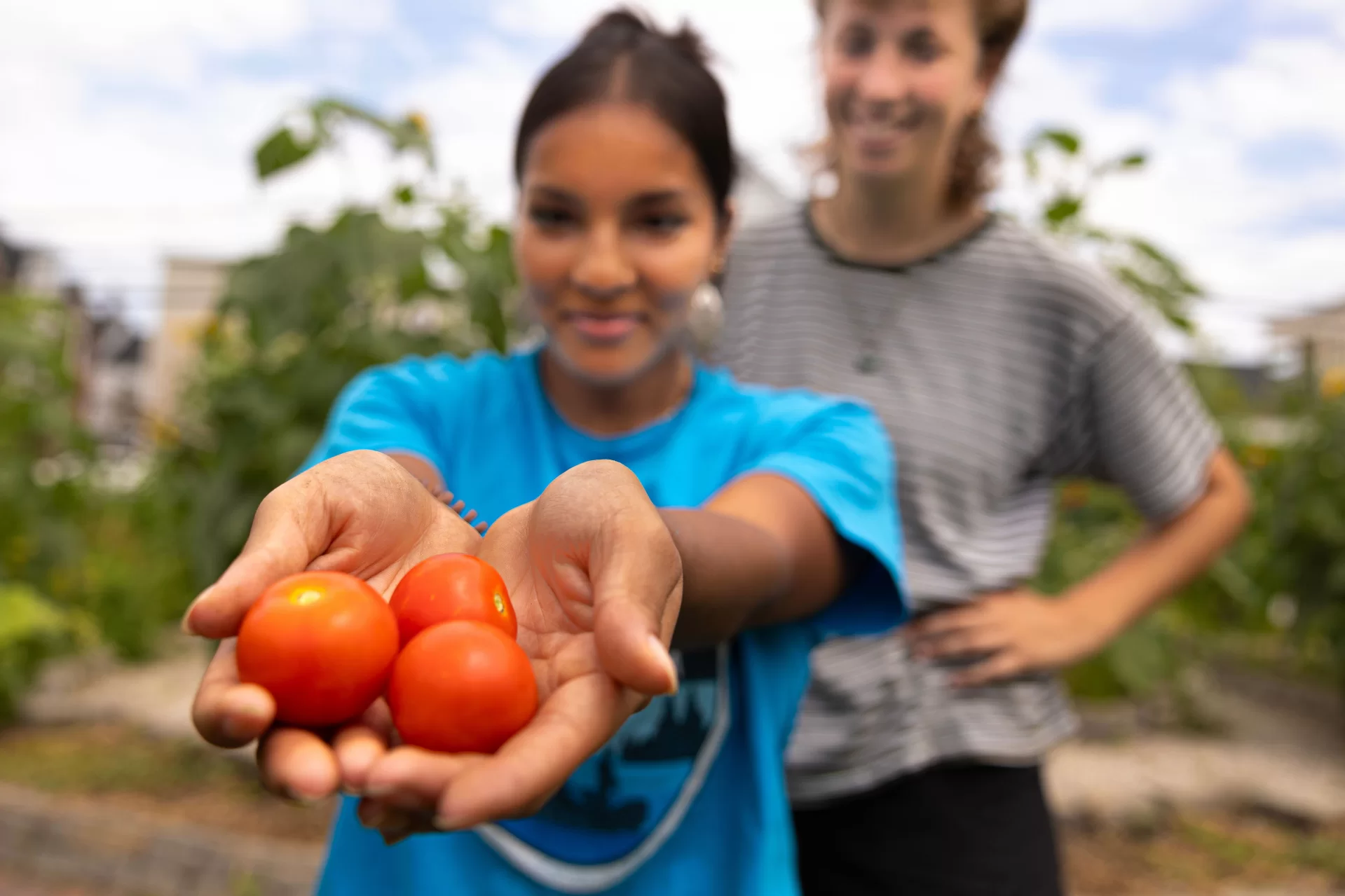 person holding small tomatoes while another person looks on