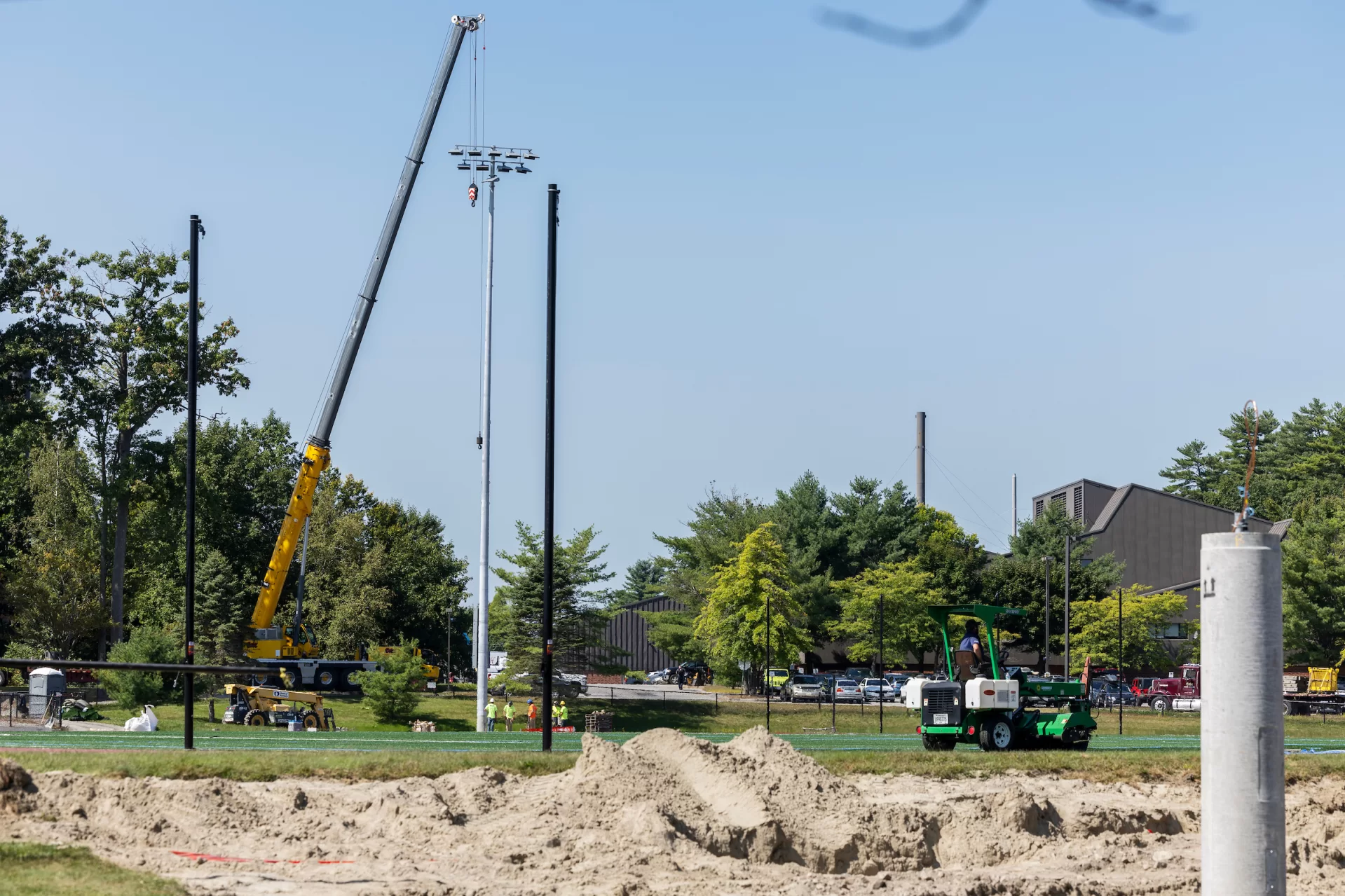 A construction team uses a crane on Russell Street Field while placing four field lights as part of the soccer field’s summer 2024 renovation on September 5, 2024.

(Theophil Syslo | Bates College)