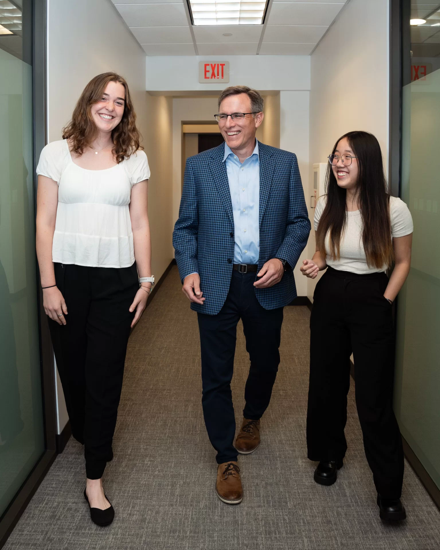 three people walking down a business hallway.