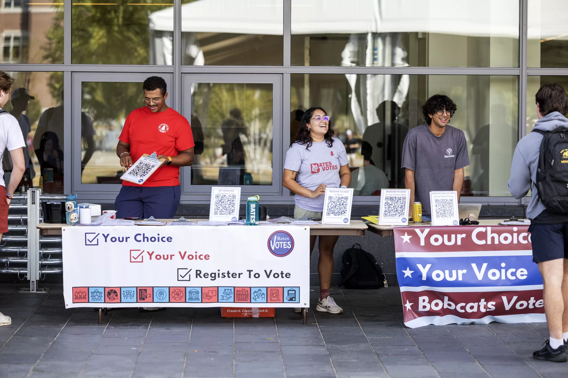 Alex Appleton ‘27 of White Bear Township, left, Ananya Rao ‘25 of Bedford, N.H., center, and Neil Grover ‘27 of Avon, Conn., right, station a table outside Commons during National Voter Registration Day on September 17, 2024. (Theophil Syslo | Bates College)