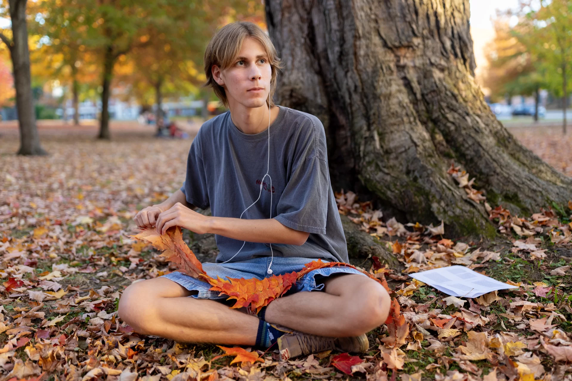 A student sews colorful fall leaves together to make a necklace.