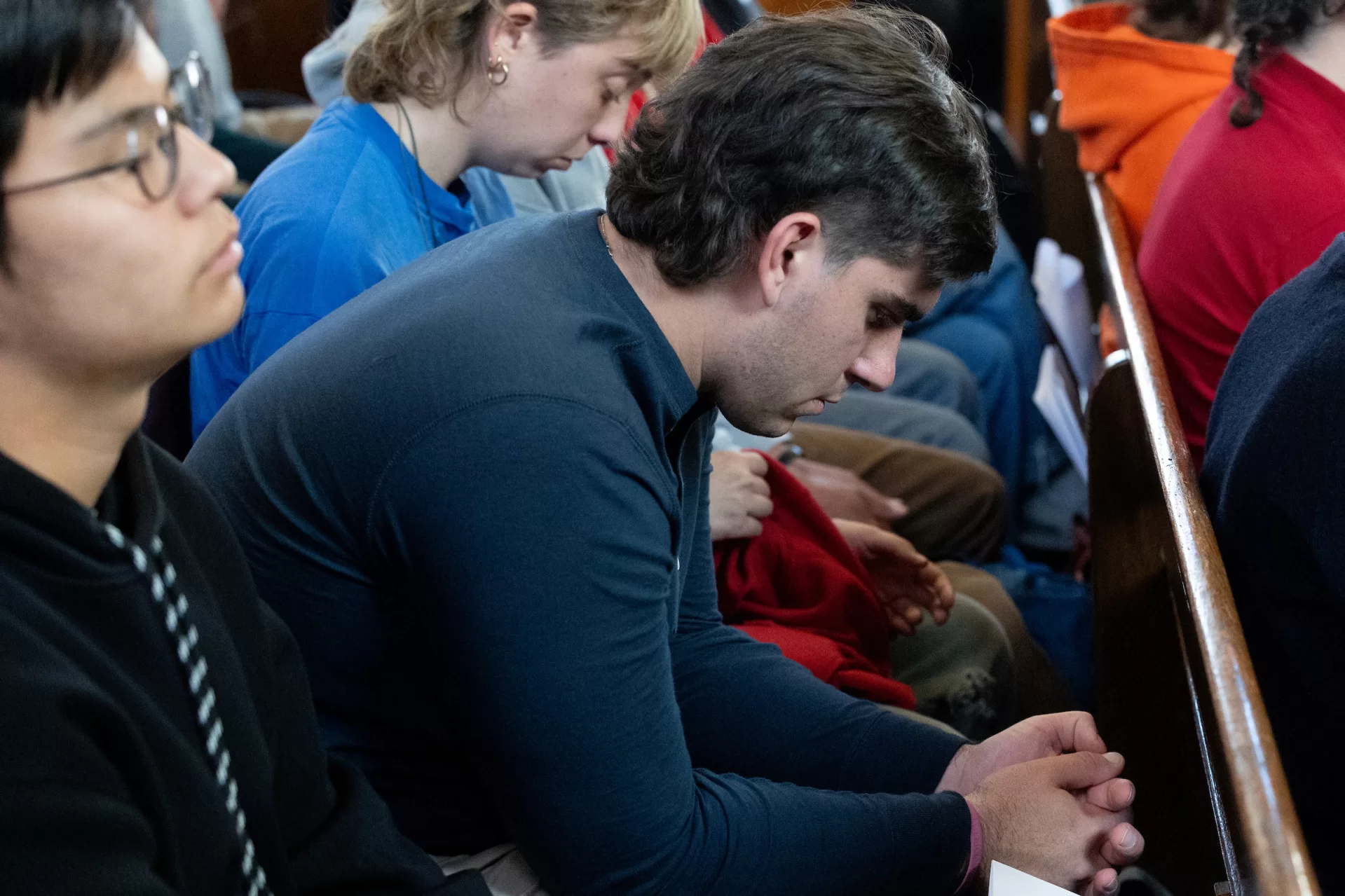 During the one-year Remembrance Service in Gomes Chapel, a student bows his head during the reading of the names of the 18 people killed in the mass shootings in Lewiston on Oct. 25, 2023. (Phyllis Graber Jensen/Bates College)