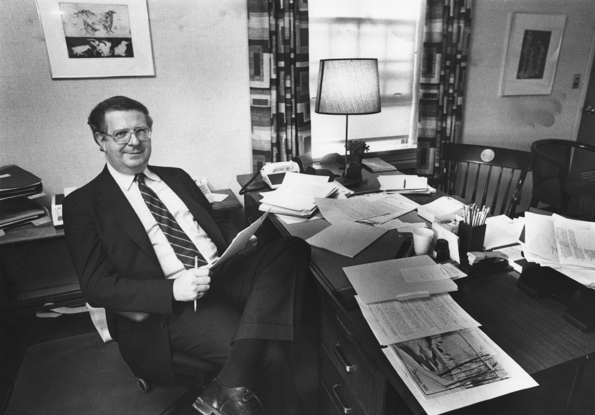 man in coat and tie sitting at an office desk