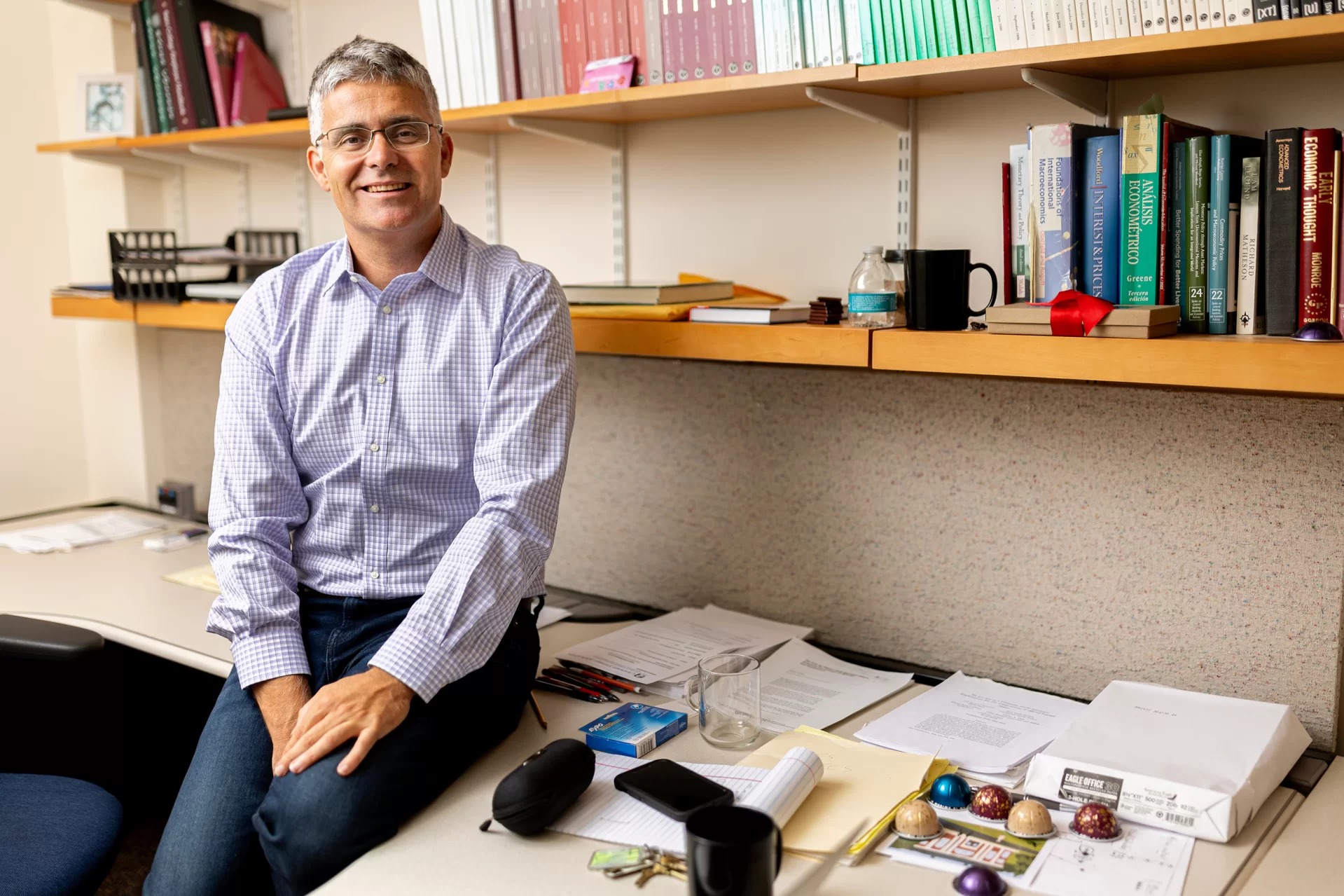 Man sitting on a desk with bookshelf