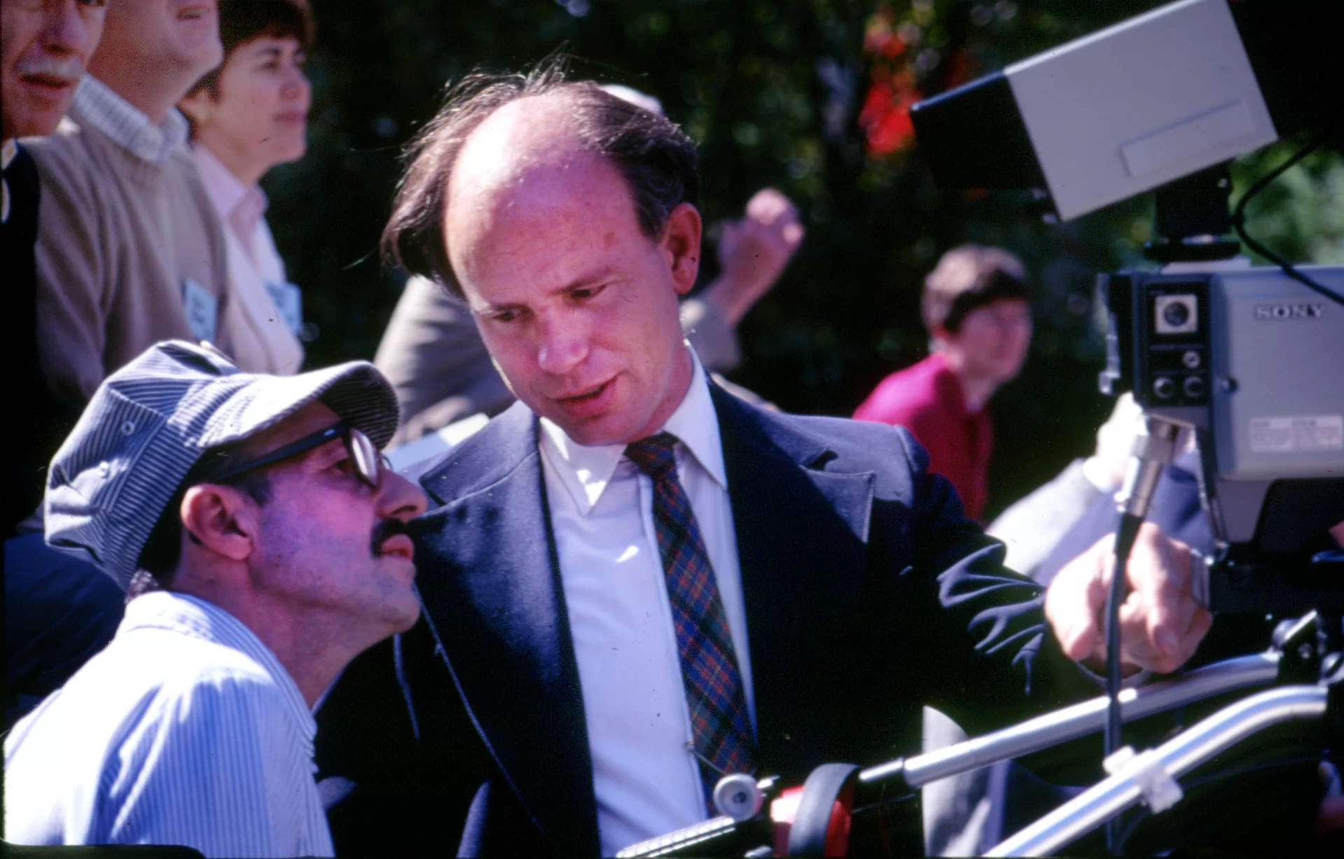 two men looking at a video camera viewfinder.