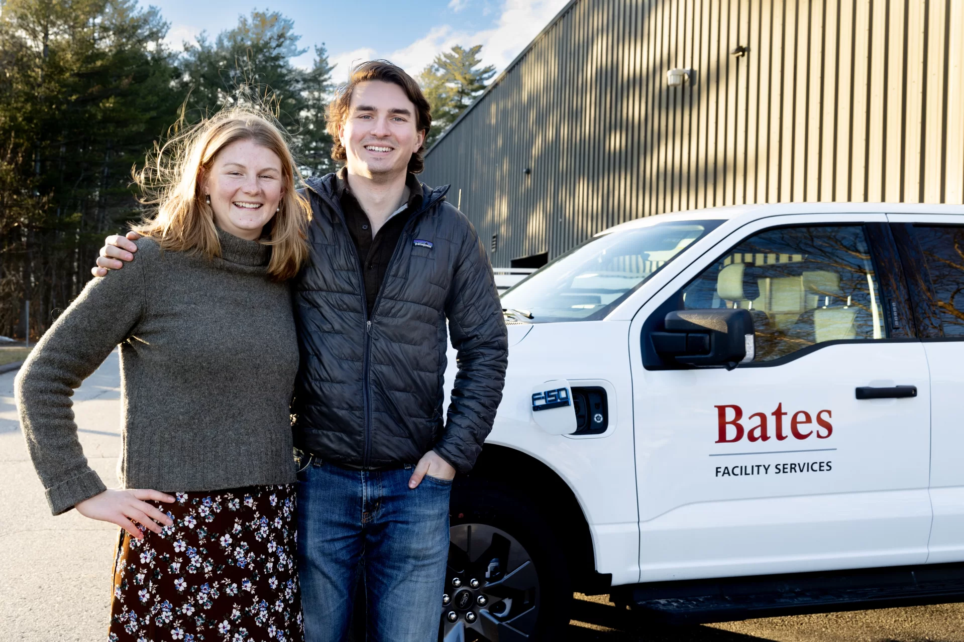 two students standing in front of a pickup truck