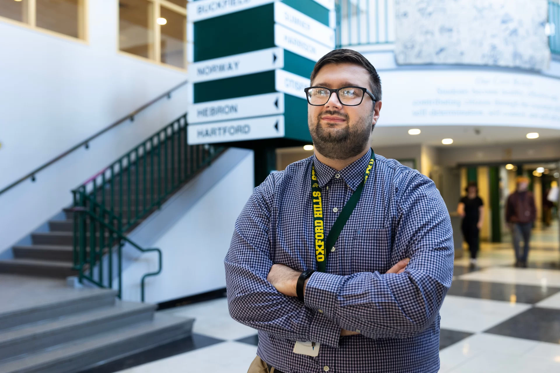 Travis Palmer ’21
OHCHS Social Studies Teacher 
Rumford Planning Board Chairperson
He/Him/His

Photographed midday on Jan. 14, 2025 at Oxford Hills Comprehensive High School, where he poses in the main lobby of the school, outside of his second floor classroom, and with his study hall group that he begins with a “restorative” conversation (what do you hope to accomplish in this class this semester?). He is also shown standing next to a civil rights team (that he founded at the school) bulletin board.