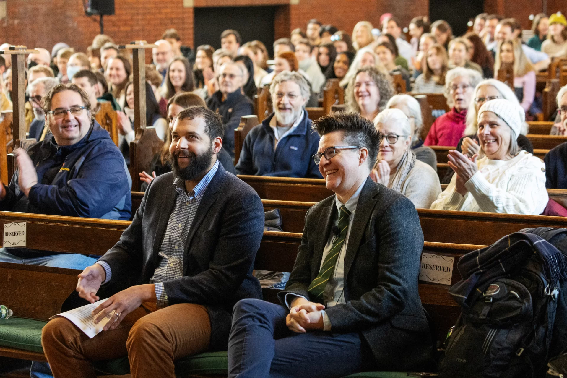 two people smiling in a crowd in a chapel