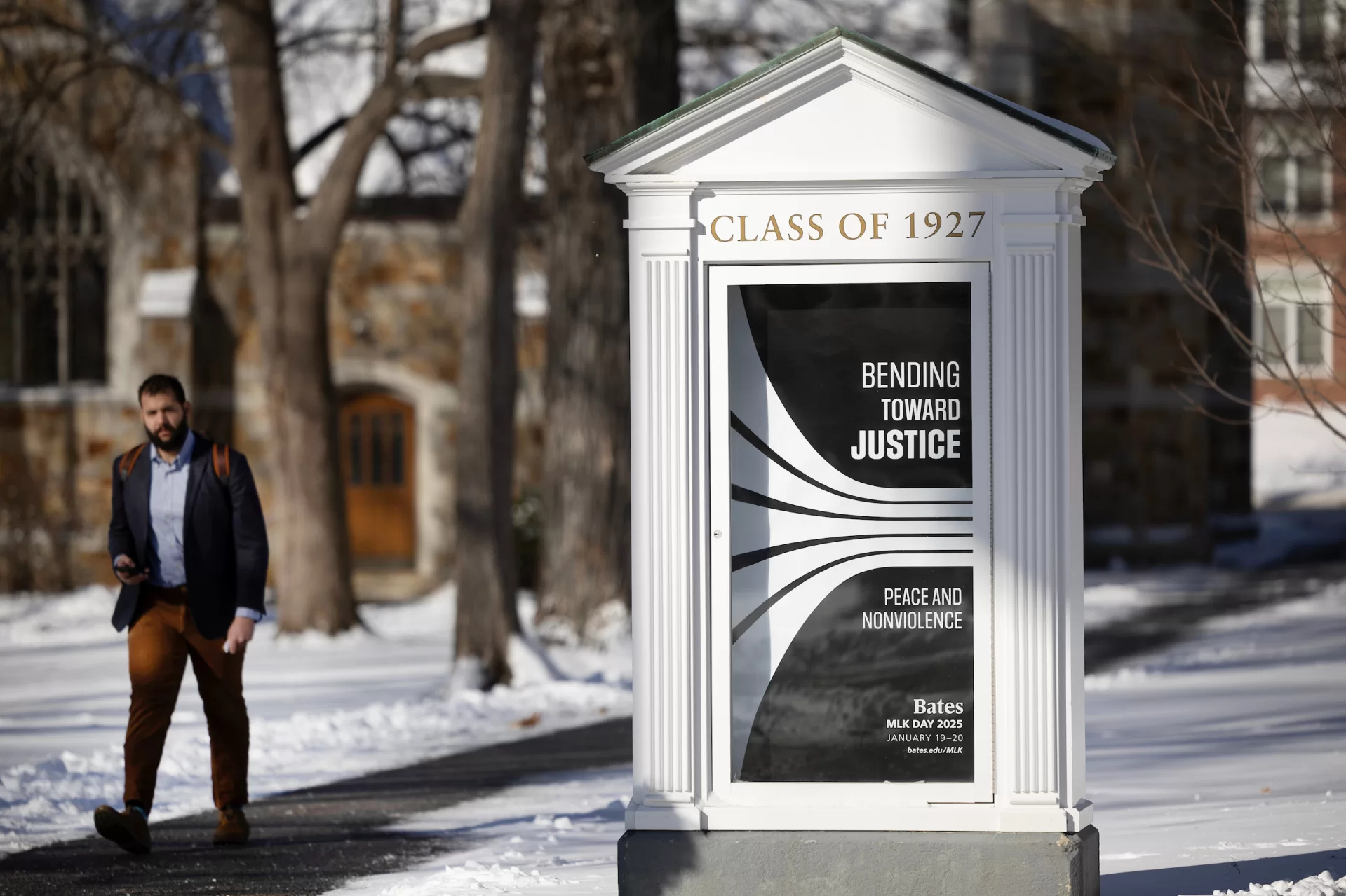 Assistant Professor of Environmental Studies Tyler Harper, who chairs the college's Martin Luther King Jr. Day Planning Committee, walks past the Mouthpiece featuring this year's poster for the MLK Day theme, "Bending Toward Justice: Peace and Nonviolence."