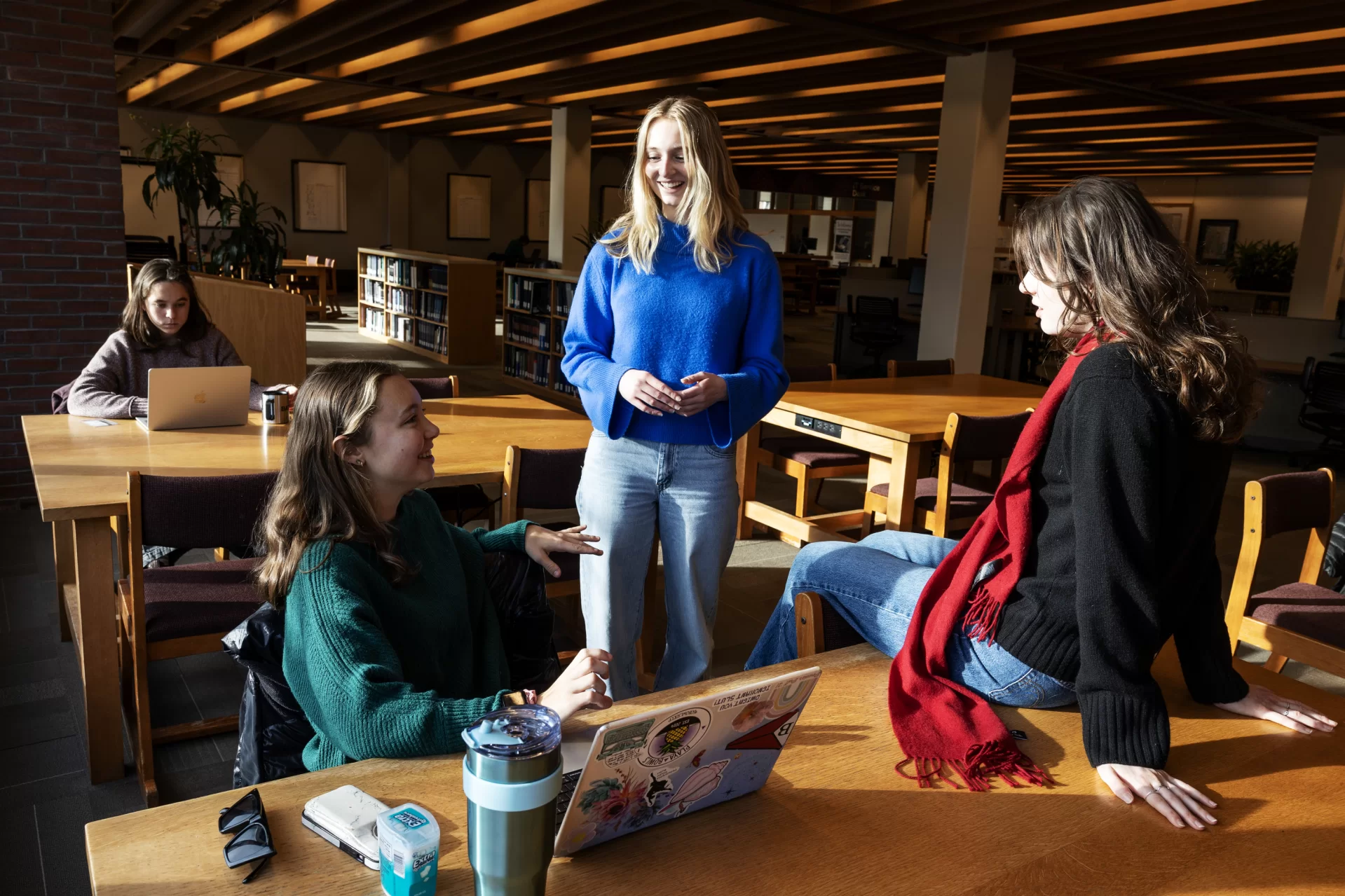 Lilah Rousso ‘25 of England, left, Sam Manogue ‘26 of Wynnewood, Penn., center, and Lydia Frew ‘25 of Norwich, Vt., right, “catch up” in the library on the first day of winter semester classes on January 8, 2025. (Theophil Syslo | Bates College)