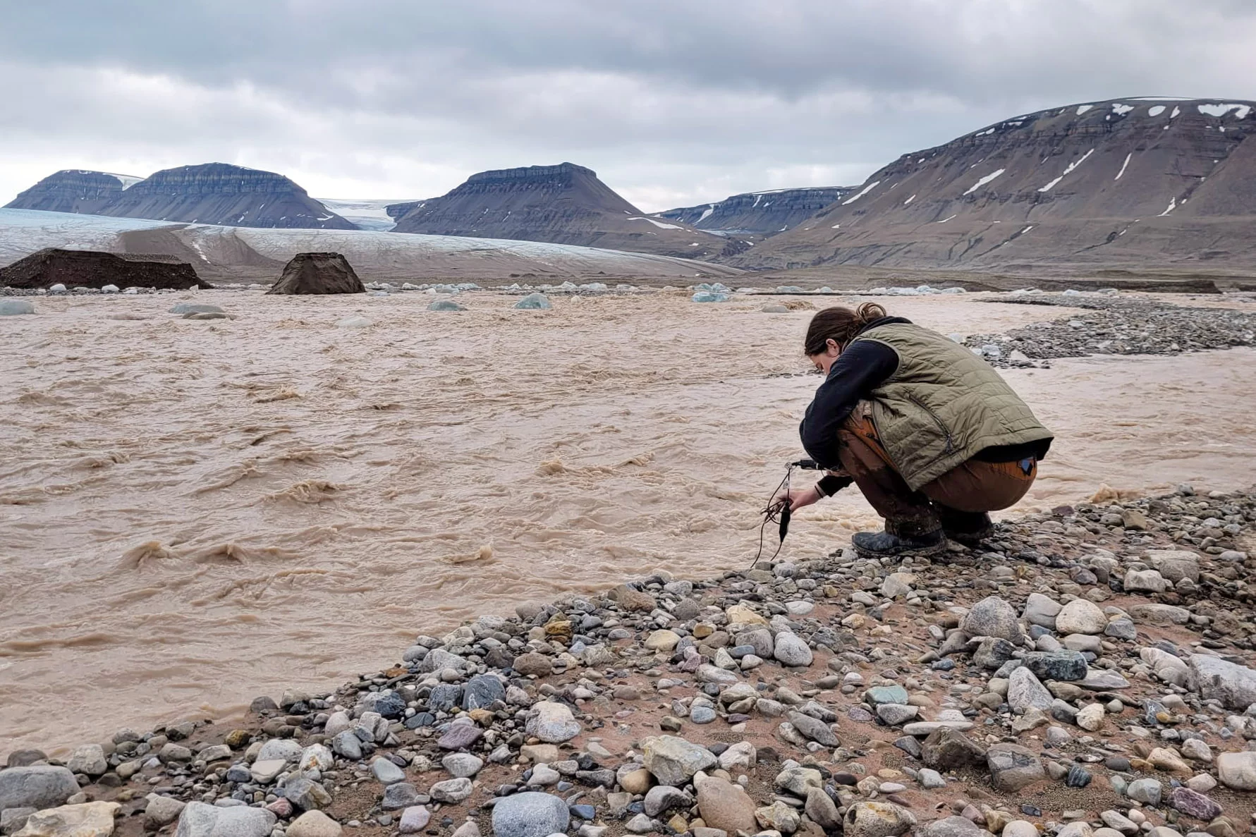 person taking water sample from river