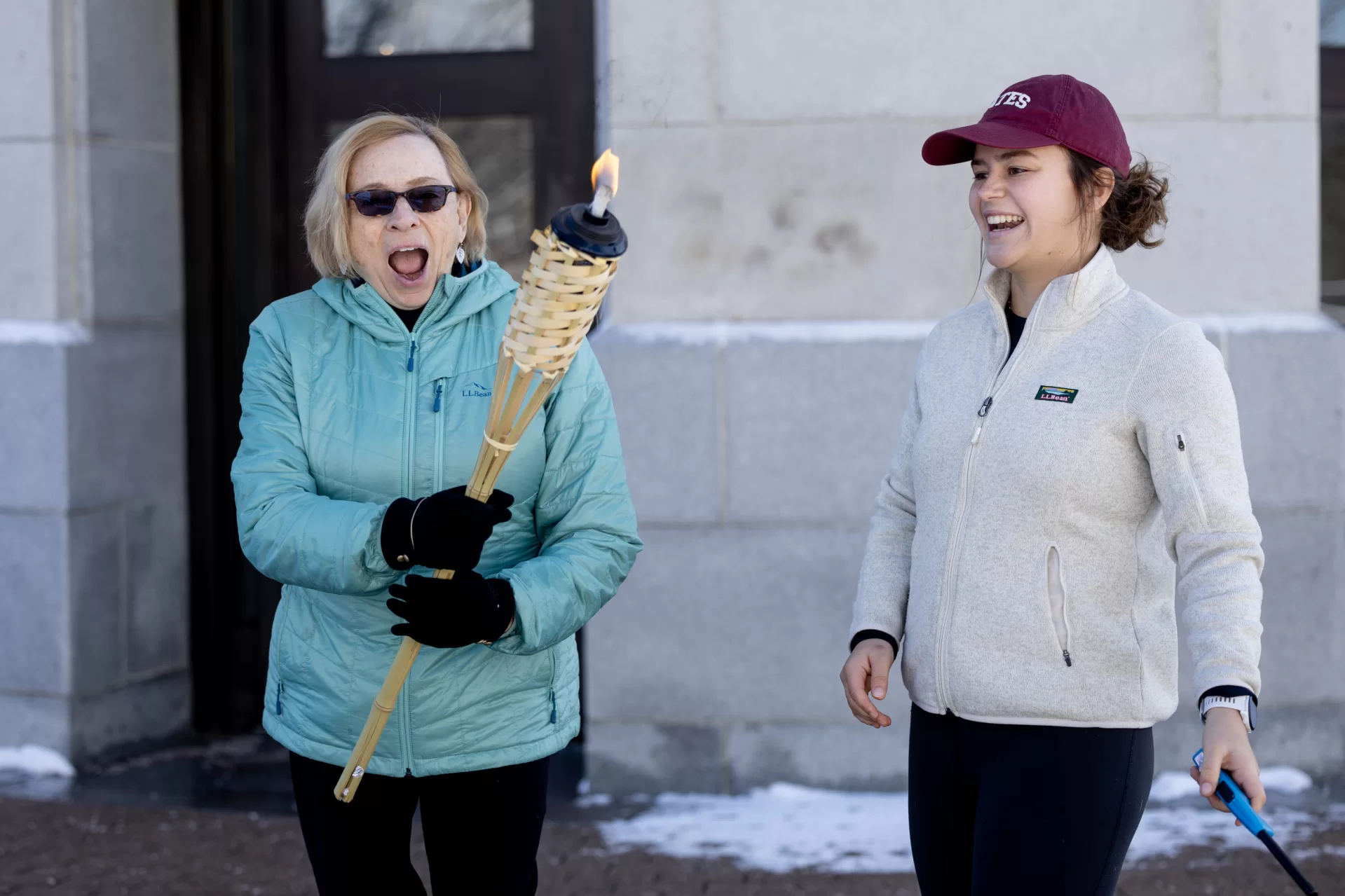 It wasn’t your typical “run” of events.

Though Thursday’s weather slightly impeded upon Winter Carnival plans, the Bates Outing (@batesoutingclub) and Running Clubs still found a way to make the annual Torch Run happen.

Running club member Ellie Schueler ’25 of Colorado Springs, Colo., and club co-president Alden Zhang ’26 of Bethesda, Md., headed up to Augusta Friday morning for the ceremonial lighting of the torch, a tradition since 1958 when Maine Governor Ed Muskie lit the torch for the first Torch Run, created by the Outing Club.

Outside of the Maine State House, Maine @governorjanetmills joined in on the festivities and helped Schueler ’25, pictured in the first slide, light the torch, shielding the budding flame from cool winds.

At this point, students participating in the Torch Run would typically begin their run from Augusta all the way back to campus in a relay-style race, taking turns so that each participant runs a few miles.

But, four-and-a-half inches of snow on Thursday evening and Friday morning snow squalls meant the roads were not fit for torch running. Instead, Schueler, the first runner of the day, took the torch for a quick jog before the students headed back to Lewiston to complete a relay around campus. The last runner of the day will pick the torch back up before heading to Lake Andrews, flame in hand, to signal the beginning of the Puddle Jump.

“I think it's really awesome to see everybody on campus getting together in celebration of the season,” Schueler says. “The energy is always super high around campus.”