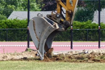 On July 15, a Shaw Bros. excavator scrapes up the natural turf laid at Russell Street Field back in 2019. A manufactured surface will replace the grass. (Doug Hubley/Bates College)