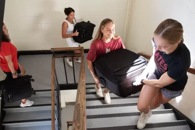 Olivia Szachta ’25 of Duxbury, Mass., from left, Willow West  ’27 of Shirley, Mass., Kate Leland ’28 of Arlington, Va. and Gwyn Jamison ’28 of Steamboat, Colo., help move first years students into Parker Hall during Bates’ Opening Day on August 29, 2024.