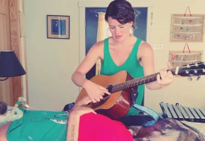 Music therapist playing guitar for patient